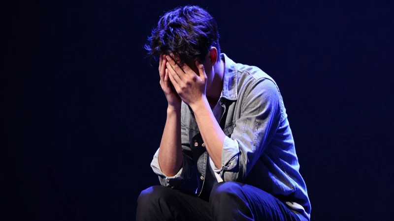 Joven actor triste en escenario dramático