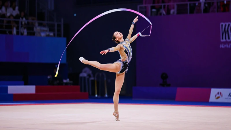 Qué es la gimnasia rítmica y cómo se compite en ella 9 Gimnasta elegante con cinta en competición vibrante