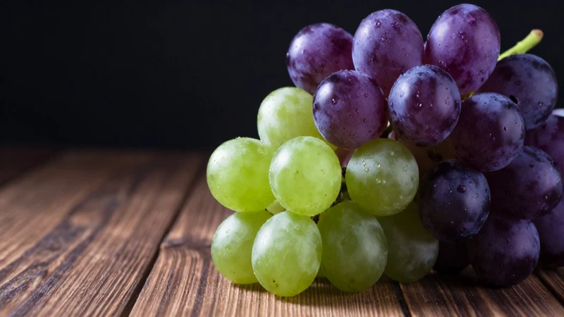 Cuáles son la definición, beneficios y concepto de la uva 7 Uvas violetas y verdes, realistas, sobre madera
